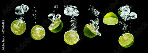 Fotografia Bunch of lime fruits halves sinking with bubbles into water isolated against black background