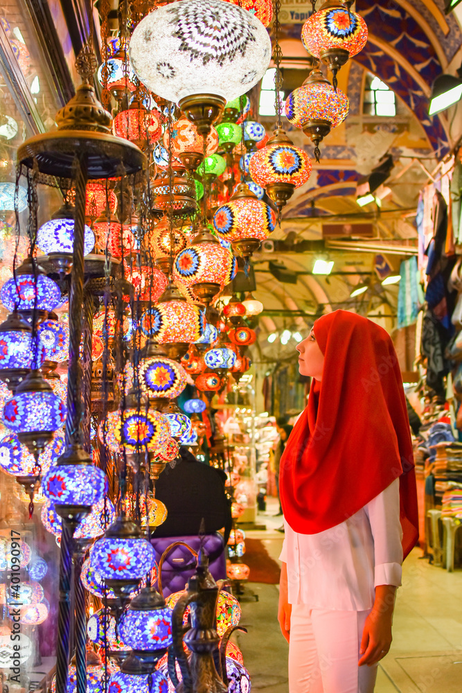Φωτογραφία Young pretty tourist Muslim woman with red scarf looking on Traditional Turkish lamps in souvenir shop