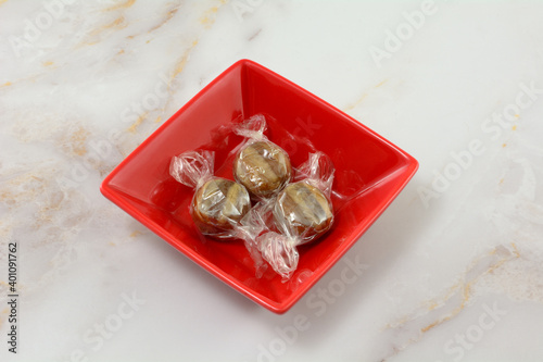 Christmas peppermint humbug candy individually wrapped in red candy dish on table