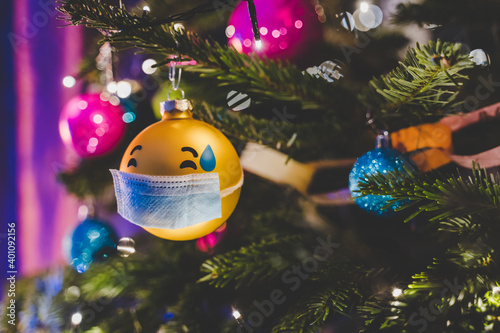 Covid-19 christmas emoji ball with face mask hanging on christmas tree