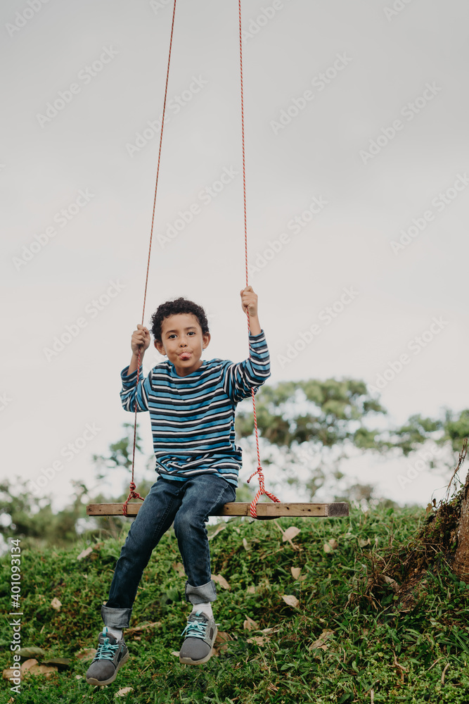 African American boy swinging on a swing in nature African American boy swinging on a swing in nature