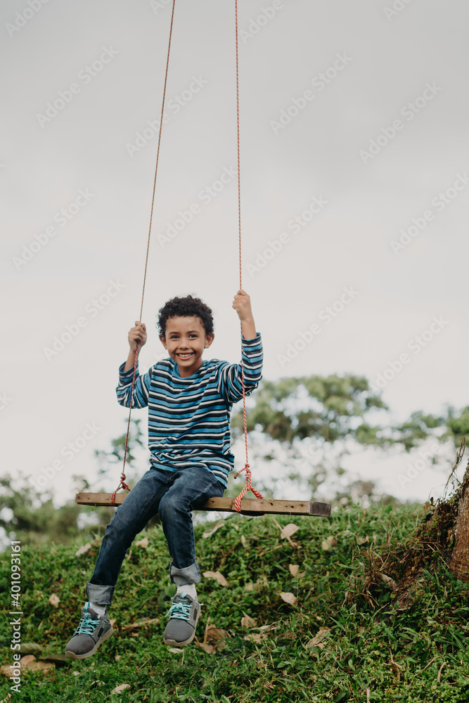 African American boy swinging on a swing in nature