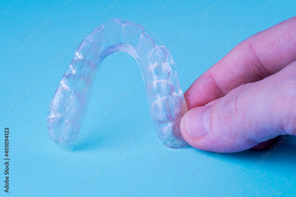 HAND HOLDING AN OCCLUSAL SPLINT. JAW NIGHT GUARD STABILIZATION. TEETH