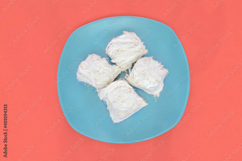 Turkish traditional dessert - Cotton Candy (aka Pismaniye) with Color of year 2019 Living Coral as background. Top view. Copy space for text. Trendy color concept. Creative food minimalism. 