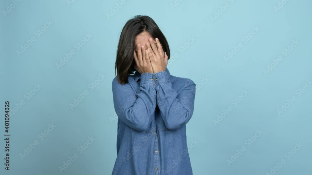 Young latin woman covering eyes by hands and looking through the fingers over isolated background