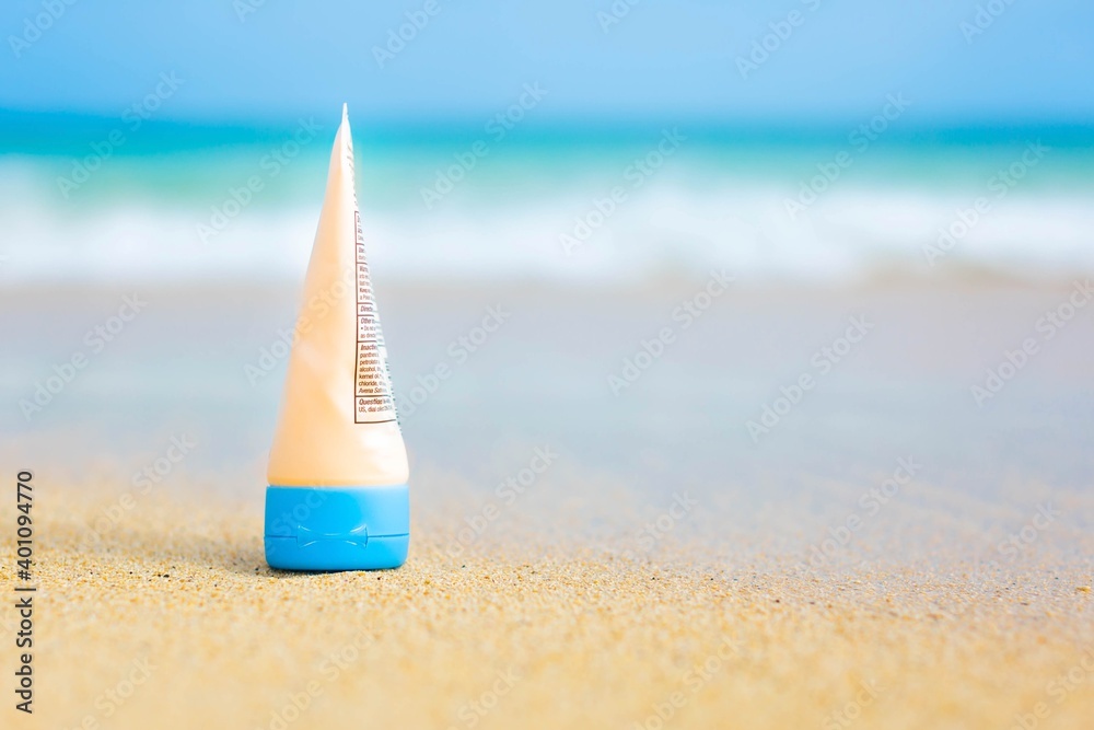 A bottle of sunblock sitting on the sand on a sunny beach day. Uv sun protection. A bottle of sunblock sitting on the sand on a sunny beach day. Uv sun protection.