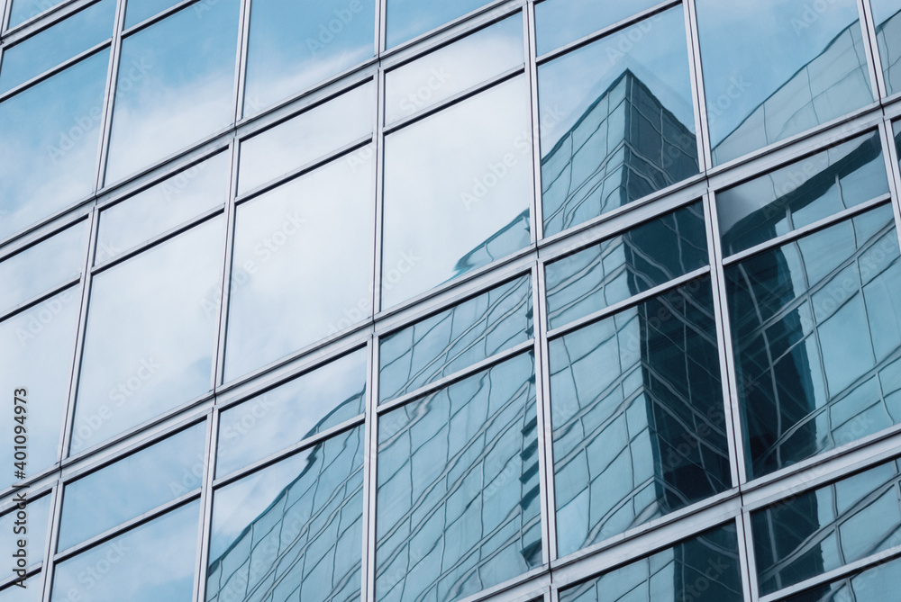 glass wall reflecting modern glazed office building and sky for business background