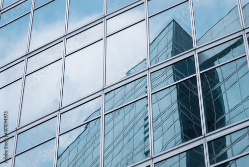 glass wall reflecting modern glazed office building and sky for business background