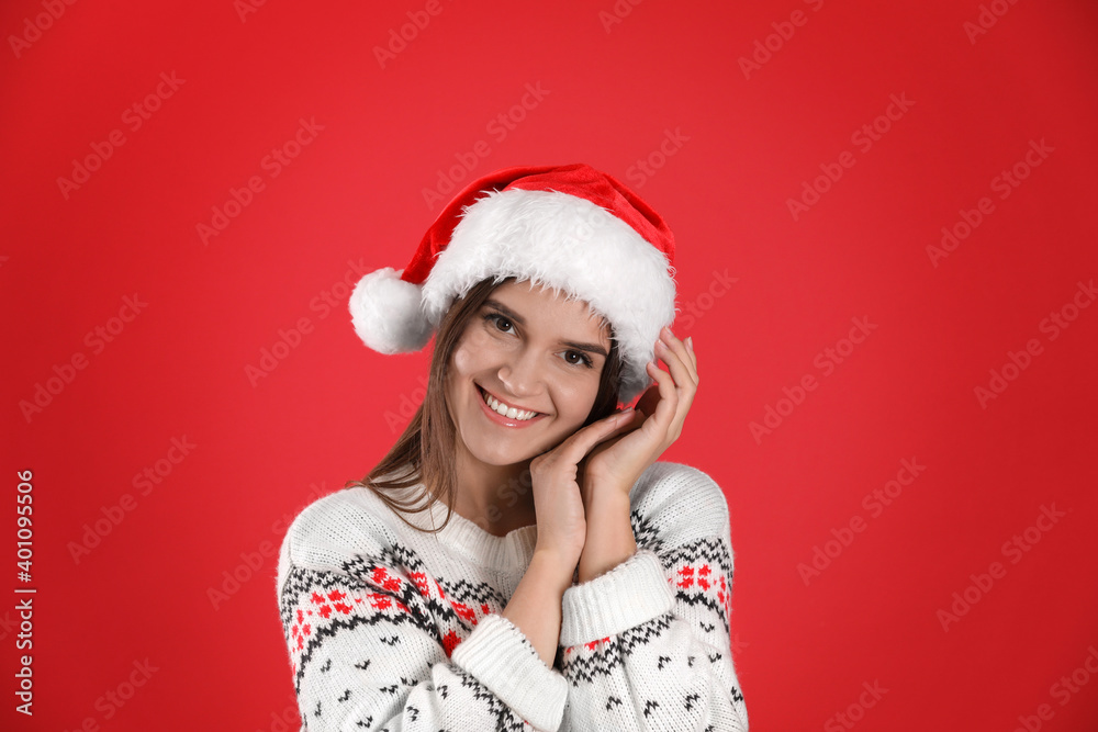 Pretty woman in Santa hat and Christmas sweater on red background Pretty woman in Santa hat and Christmas sweater on red background