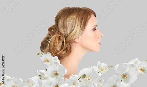 Beautiful young woman and orchid flowers on light background. Spa portrait