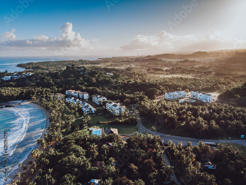 Aerial drone view of the paradise beach with tropical residence, palm trees and blue water of Atlantic ocean at sunrise, Las Terrenas, Samana, Dominican Republic