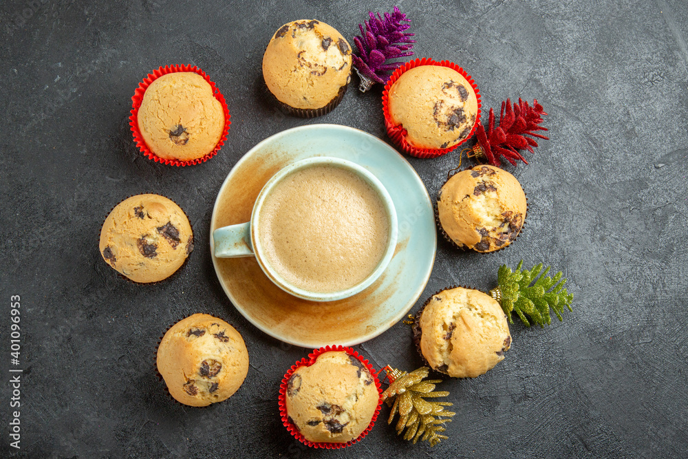 Above view of delicious coffee around small cupcakes and new year decorations on dark background Above view of delicious coffee around small cupcakes and new year decorations on dark background