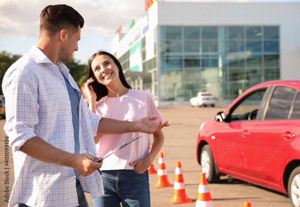 Instructor with clipboard and his student near car outdoors. Driving school exam Instructor with clipboard and his student near car outdoors. Driving school exam