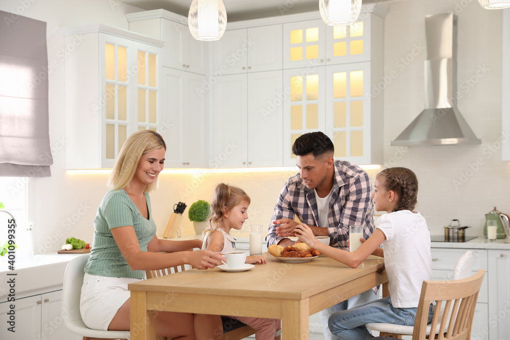 Happy family eating together at table in modern kitchen Happy family eating together at table in modern kitchen