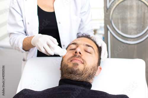 Handsome man is undergoing anti-aging ultrasound procedure at wellness center. Guy in beauty salon. Modern Cosmetology for men. Professional Cosmetologist. Men's Beauty Concept.