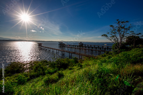 Close-up natural background of the morning scenery with the sun s rays hitting the water surface  the grassy trees on the edge of the reservoir  and the blurred wind  cool during the trip.