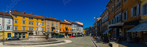 View of Victory Square (Piazza della Vittoria), central square of Gorizia with Neptune Fountain and colored buildings on sunny day, Italy