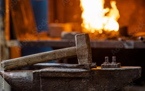 Blacksmith hammer on the anvil against the background of fire
