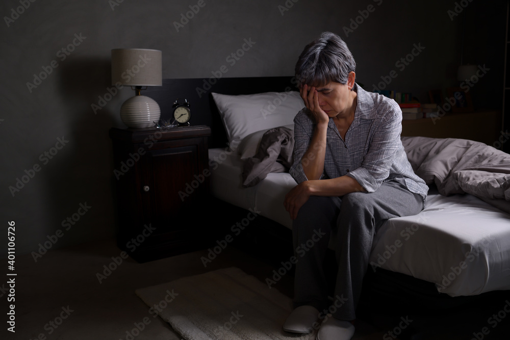 Obraz premium Depressed senior woman sitting in bed cannot sleep from insomnia