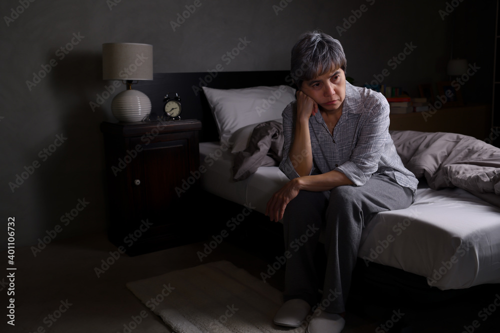 Obraz premium Depressed senior woman sitting in bed cannot sleep from insomnia