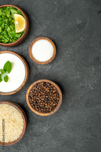top view wooden bowls with rice natural yogurt parsley black pepper salt on dark background with copy space