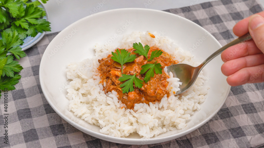 Delicious sour cream chicken paprika served with rice and fresh parsley close up on a plate on kitchen table Delicious sour cream chicken paprika served with rice and fresh parsley close up on a plate on kitchen table
