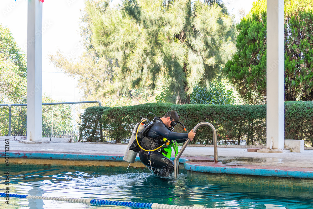 Naklejka premium diver coming out of the water by the stairs of the pool after his diving class