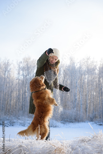A young woman plays with english cocker spaniel in wintertime, hunting dog and snow.