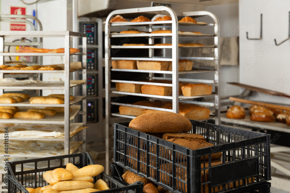 Freshly baked bread in plastic crate on table in bakery, industrial bread production