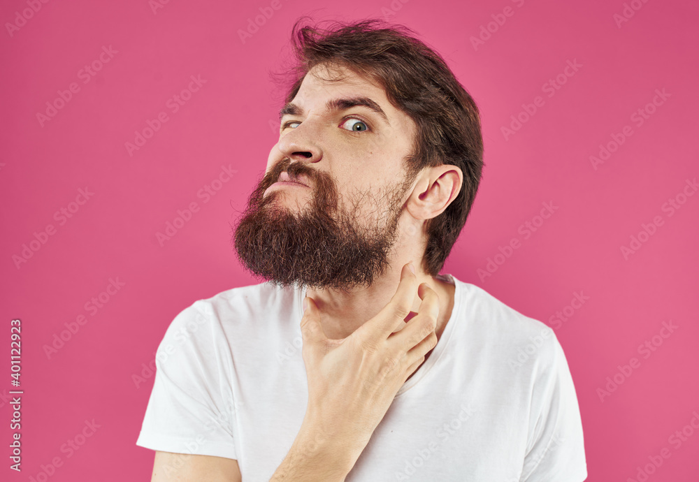 Man holds his hands near his face on a pink background stress irritability anger Man holds his hands near his face on a pink background stress irritability anger