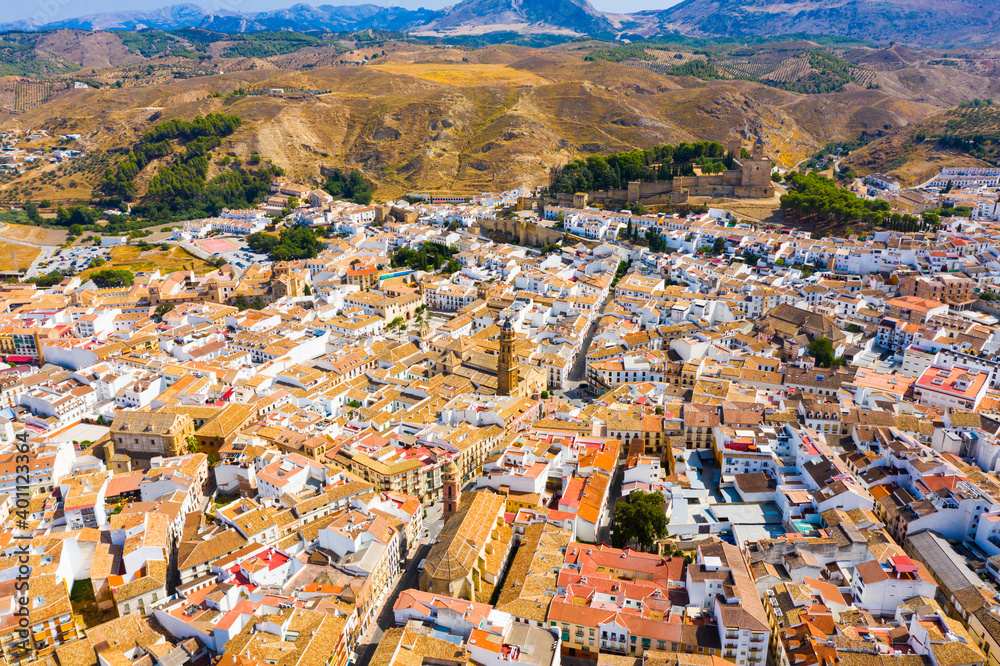 Panoramic aerial view of Antequera cityscape overlooking medieval Moorish fortress alcazaba and bell tower of San Sebastian Church, Malaga, Spain..