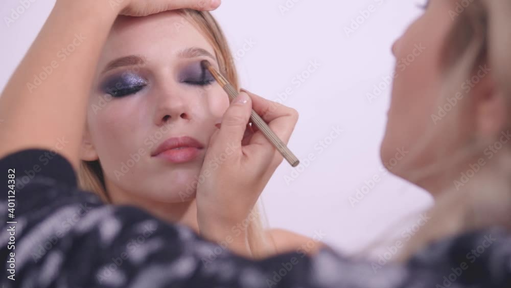 A makeup artist blends eyeshadow over the eye A makeup artist blends eyeshadow over the eye