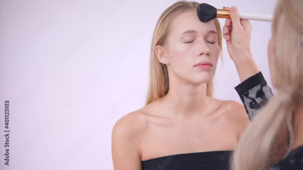 The makeup artist applies the foundation with brush The makeup artist applies the foundation with brush