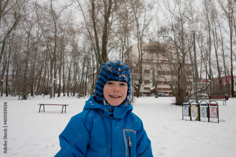 a boy in a blue winter jacket plays in a winter park and laughs happily. a boy in a blue winter jacket plays in a winter park and laughs happily.