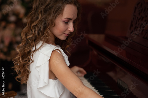 Young woman is sitting at the piano. Professional musician. Piano in a beautiful Studio. Preparation for a musical concert. Classical music.