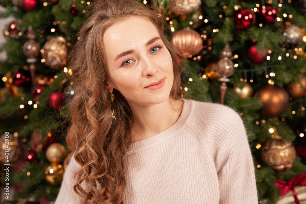 Blonde girl sitting on the background of a Christmas tree. Festive mood. To give gifts. New year's mood. Merry Christmas. Blonde girl sitting on the background of a Christmas tree. Festive mood. To give gifts. New year's mood. Merry Christmas.