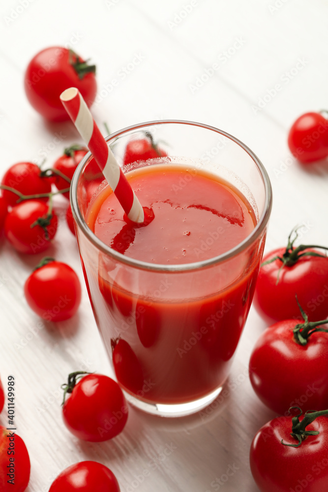 Glass with tomato juice and straw and tomatoes on wooden background Glass with tomato juice and straw and tomatoes on wooden background