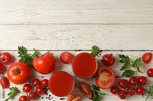 Glasses with tomato juice, tomatoes and spices on wooden background photo