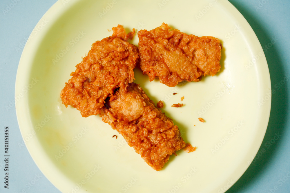 fried tempeh on yellow plate with blue background fried tempeh on yellow plate with blue background