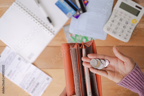 Flast lay hand woman holding coin with blur image of wallet, calculator, bookbank, book, pen, credit card. photo