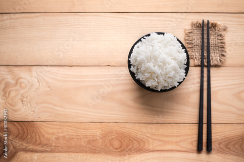 Flast lay White rice in black cup on wood background. Thai staple food concept. photo