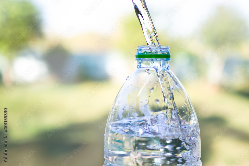 Pouring pure water into a bottle with blur image of leave green. Healthy lifestyle and ideal for environmental protection concept. Pouring pure water into a bottle with blur image of leave green. Healthy lifestyle and ideal for environmental protection concept.