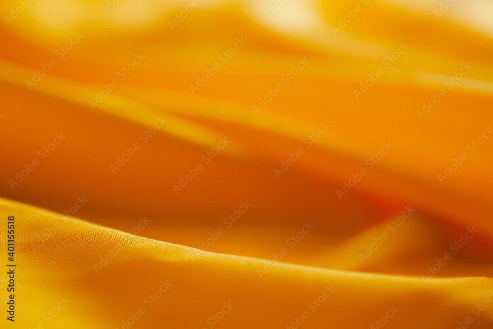 Selective focus of soft yello satin fabric for background. luxurious wallpaper of cloth. blur copy space you add text for presentation work on holidays summer.