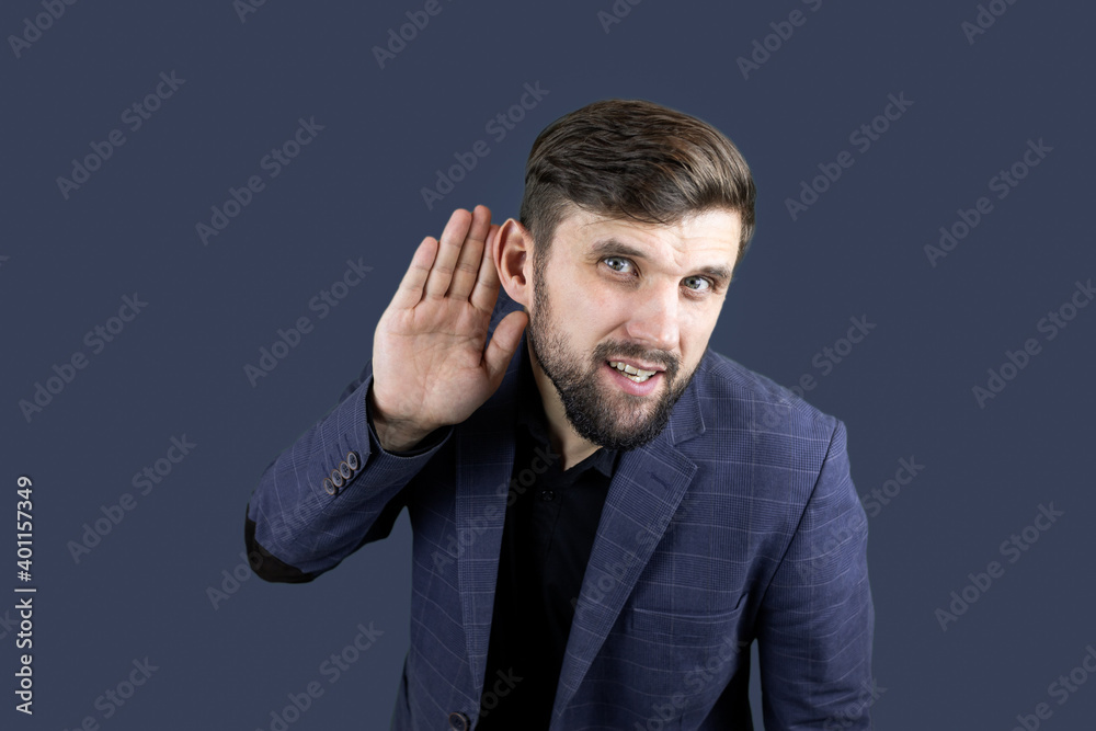 a businessman in a blue suit puts his hand to his ear, trying to hear something.