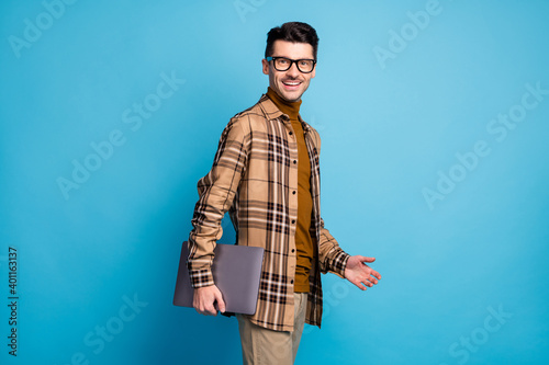 Photo of young handsome attractive smiling businessman go walk with laptop in hand isolated on blue color background