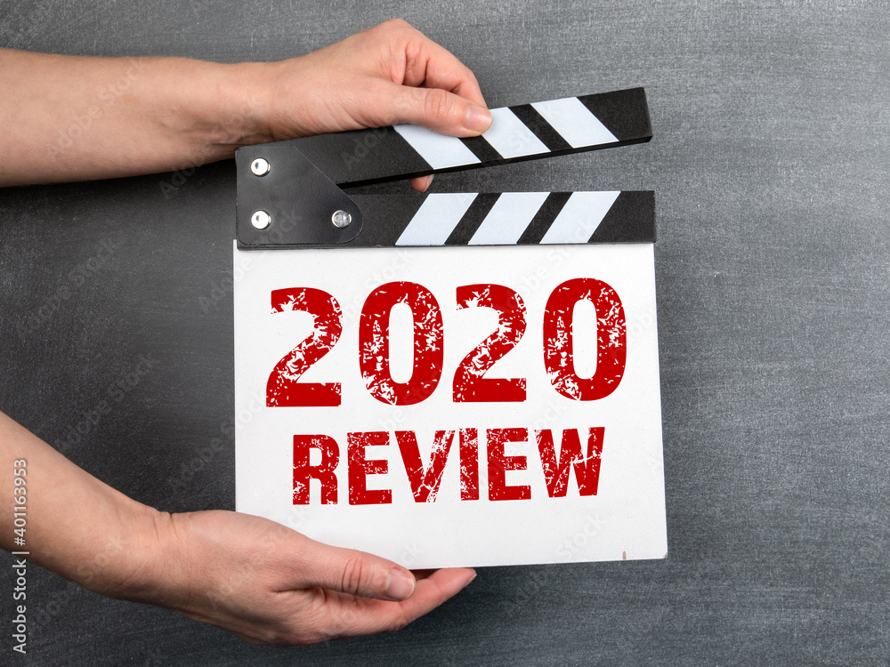 2020 Review. Business concept. Movie clapper in woman hand. Black chalk board background