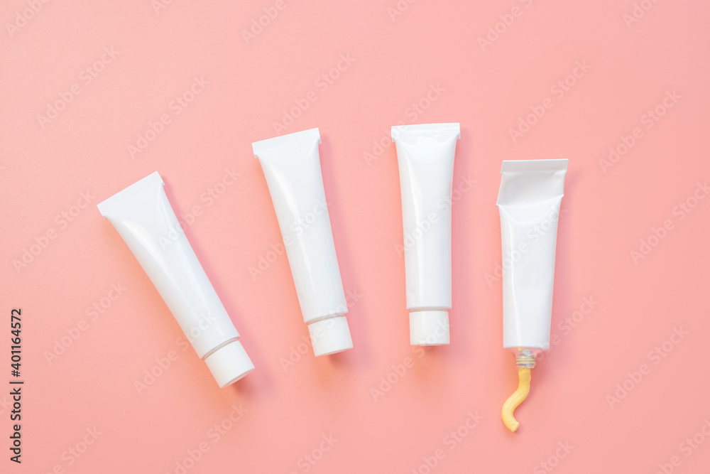White cosmetic tubes on a pink background. Concept of face and body skin care, cosmetics. Top view, minimalism, flat lay, copy space. White cosmetic tubes on a pink background. Concept of face and body skin care, cosmetics. Top view, minimalism, flat lay, copy space.