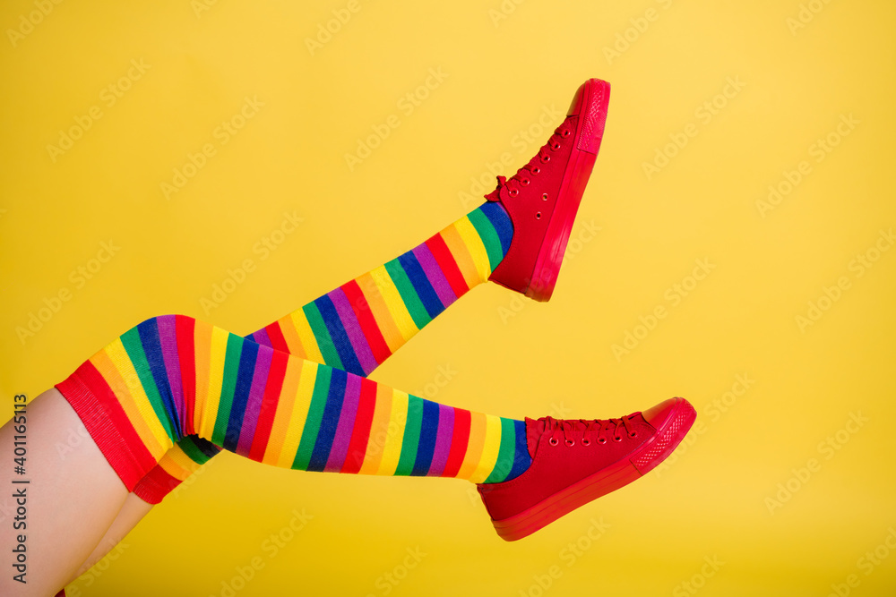 Cropped profile photo of lady playful raise legs feet wear striped knee socks red shoes isolated yellow color background Cropped profile photo of lady playful raise legs feet wear striped knee socks red shoes isolated yellow color background