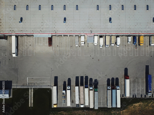 Aerial view of goods warehouse. Logistics center in industrial city zone from above. Aerial view of trucks loading at logistic center