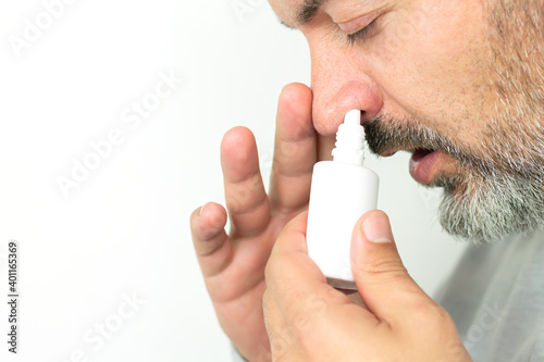 Fototapeta Naklejka Na Ścianę i Meble -  Man applying spray for runny nose, treatment of colds and flu concept
